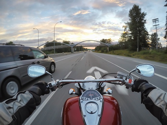 POV of a motorcyclist riding down a highway next to a minivan.