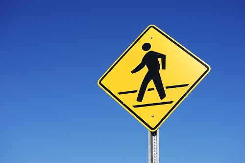 A pedestrian crossing sign behind a blue sky background